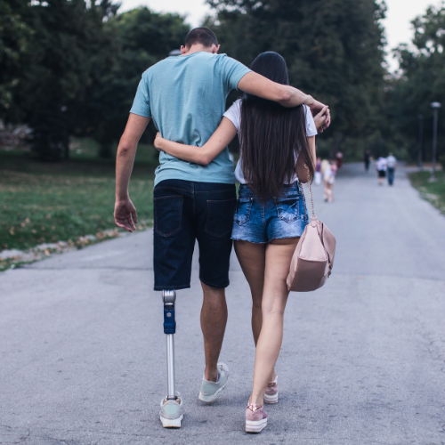Couple walking together, one partner with a prosthetic leg