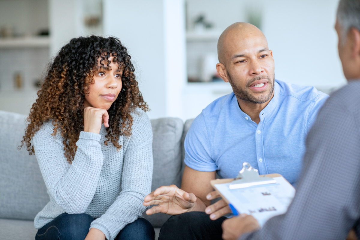 A couple sitting on a couch in a supportive counseling session with a healthcare provider